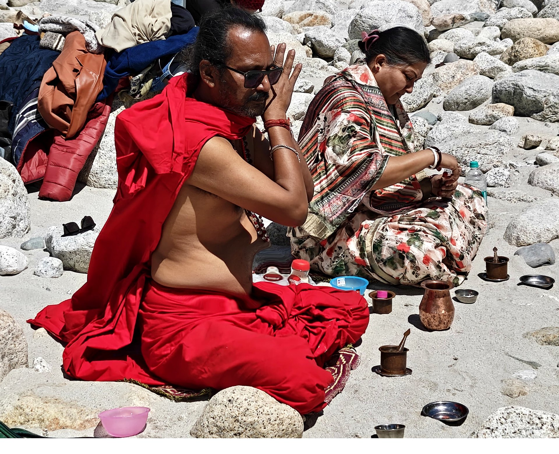 Sri Meenananda Tirthanath in pranam at a Himalayan riverbank, with Guruma seated nearby.